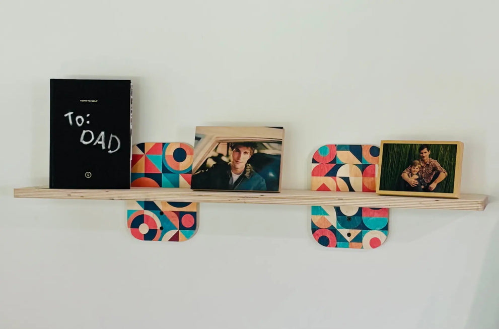 Wooden wall shelf with colorful geometric supports holding framed photos and a black book for style compact spaces
