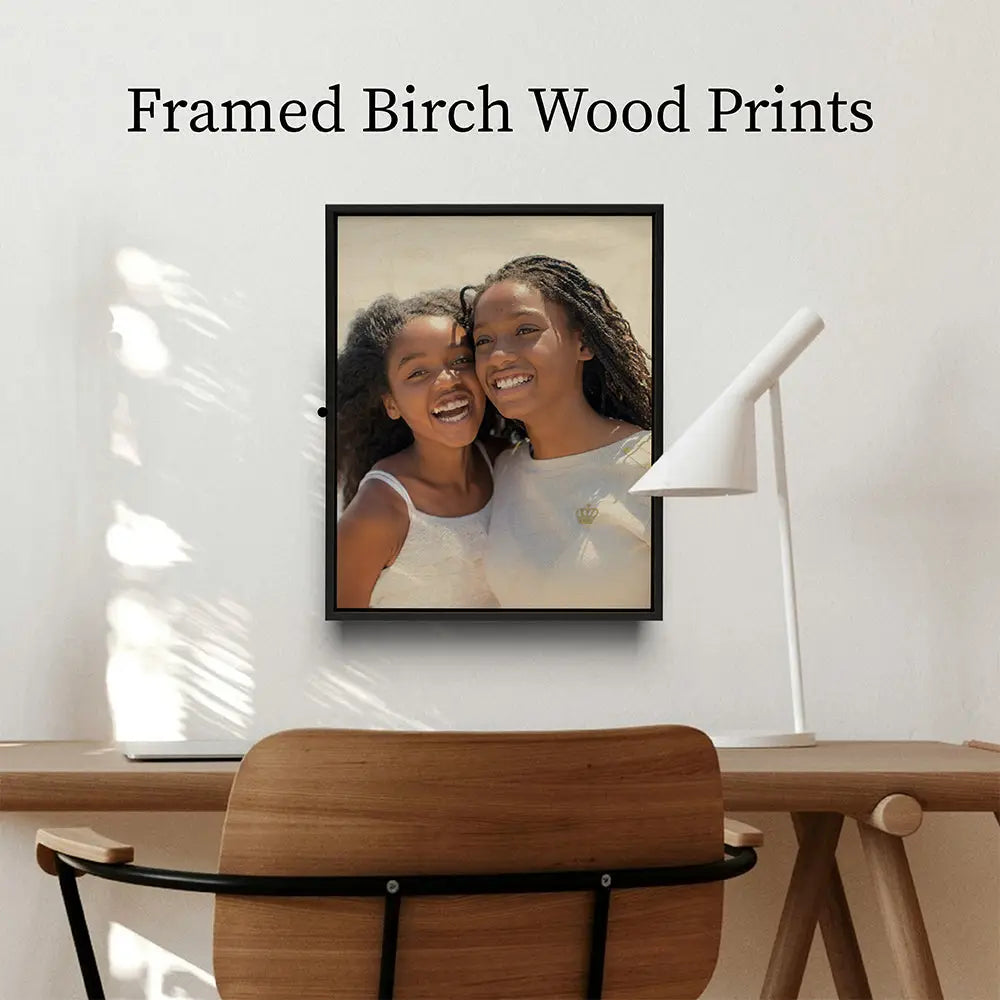 Framed photograph of two smiling people on a white wall featuring framed birch wood prints.