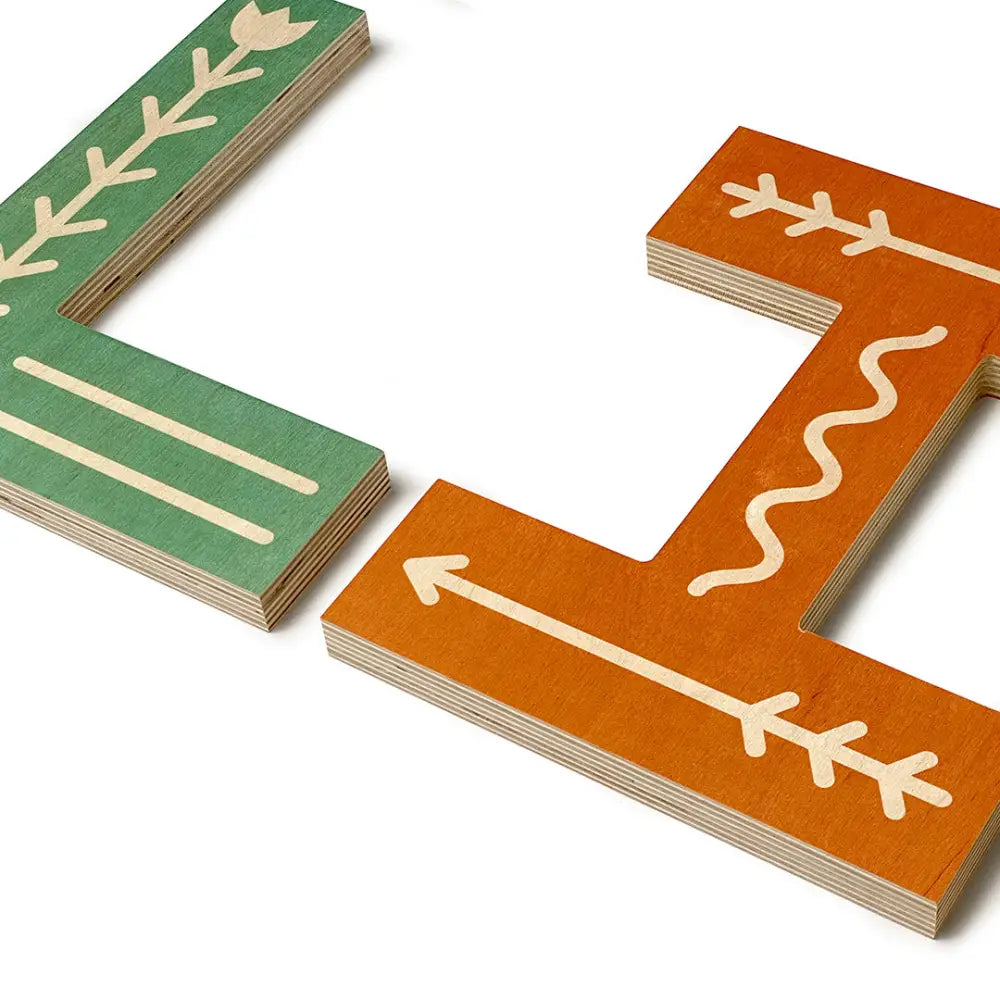 Wooden puzzle pieces with painted arrow and leaf designs in green and orange colors.