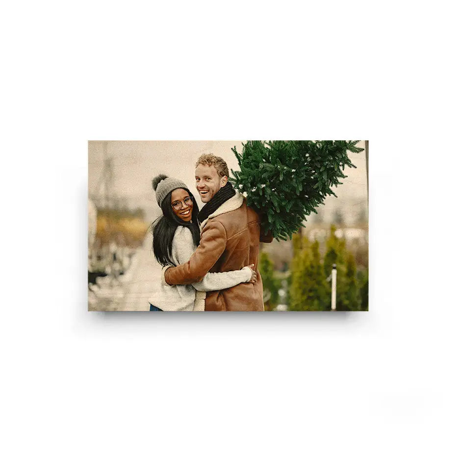 Smiling couple embracing with a Christmas tree in a 10x24 Original Cove Print