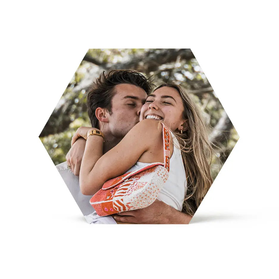 A man and woman kissing in front of a 12x12 hexagon birch photo mount print