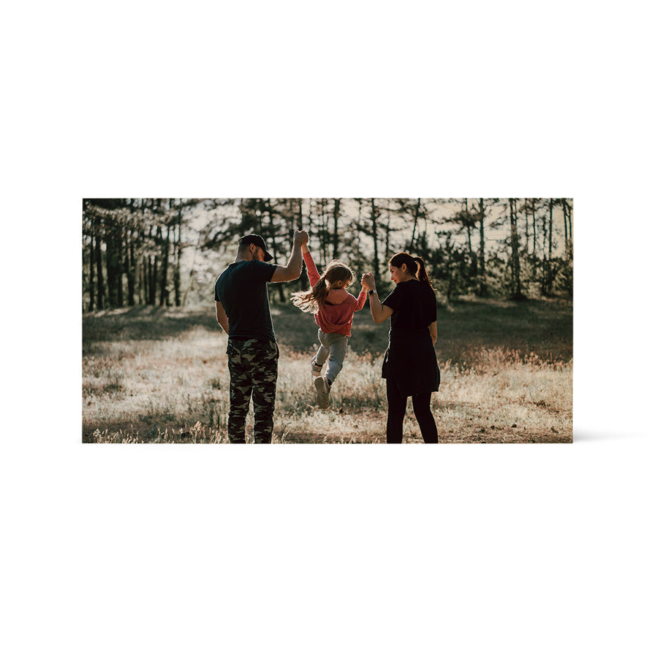 Family playing in a field displayed on a 12x24 vintage matte wood print with a photo locket