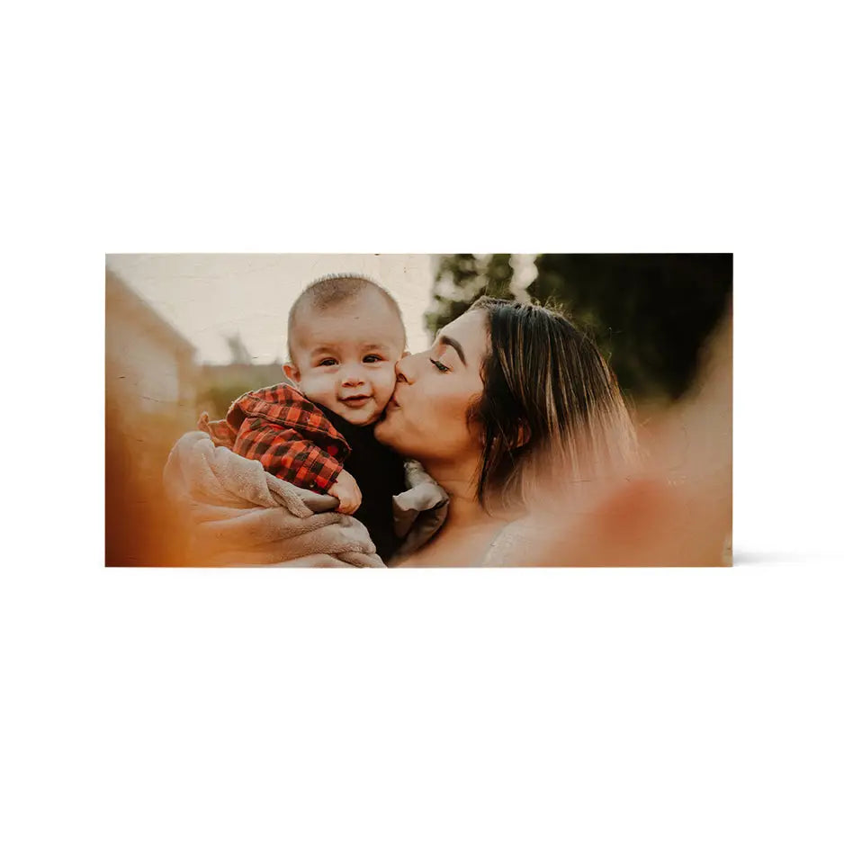 A woman kissing her baby boy on a 12x24 wood print vintage with a white background