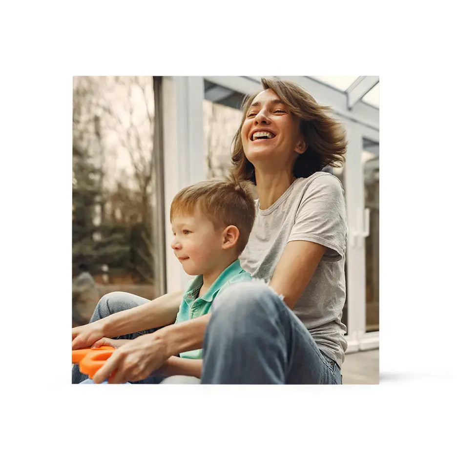 Woman and child sitting on the ground featured in a 16x16 Birch Photo Mount print