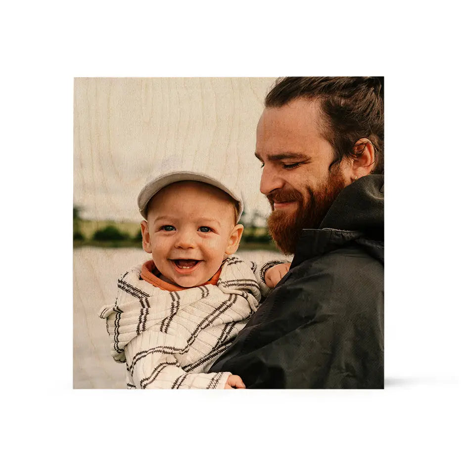 A man holding a baby in his arms on a 16x16 wood print vintage art piece