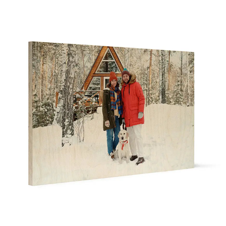 Two people in snow by an A-frame cabin on a 20x30 wood print vintage