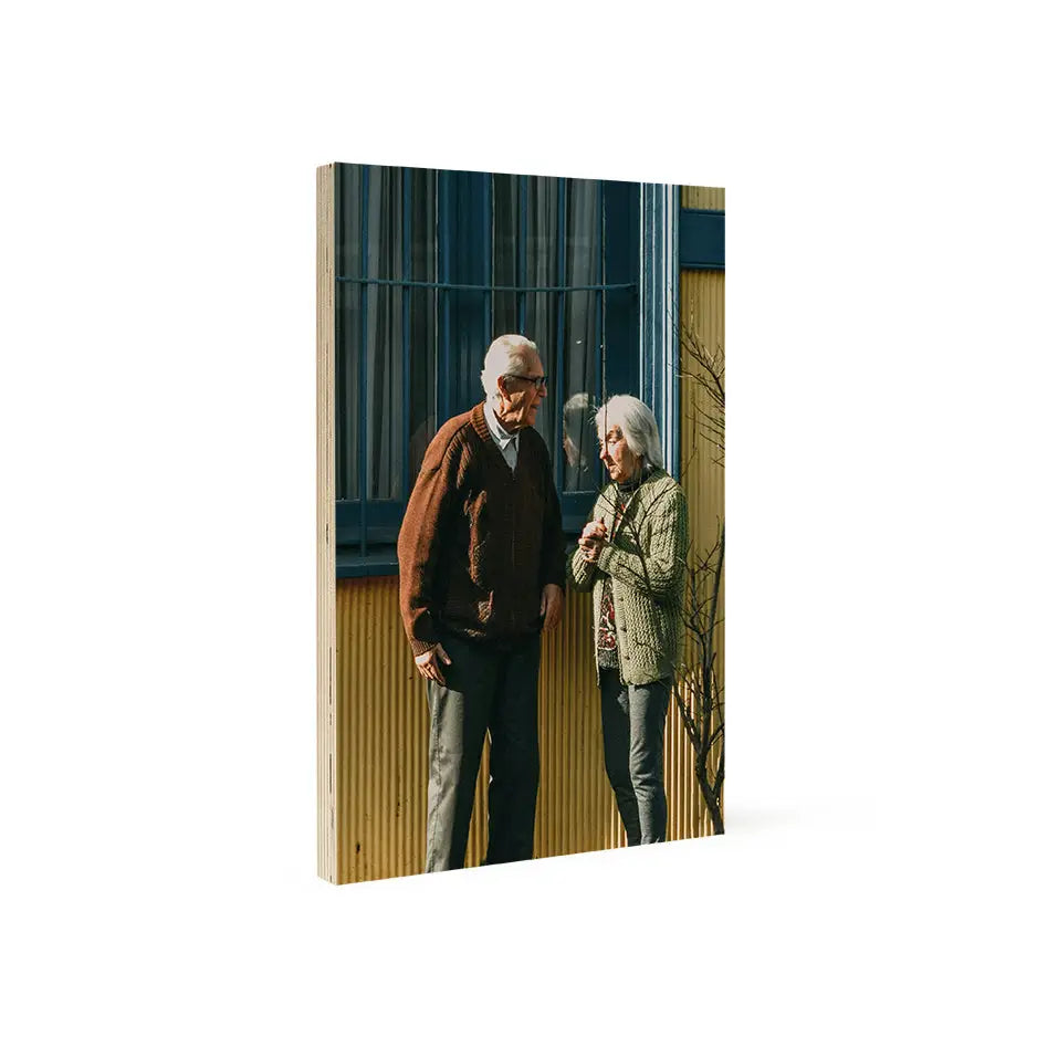 A man and woman in front of a vibrant yellow building on an 8x12 wood print