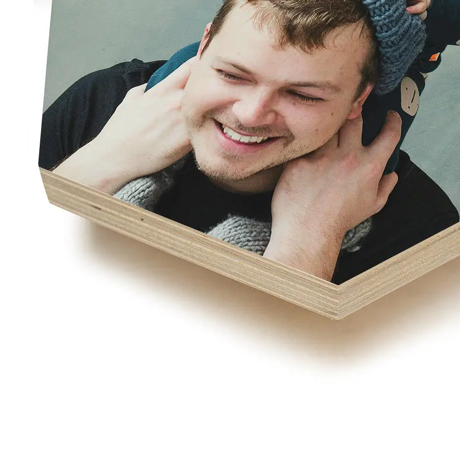 Man smiling and wearing a hat next to 8x8 hexagon wood print in bright white