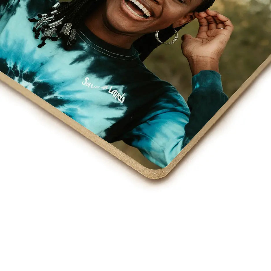 Woman in tie dye t-shirt smiling with an 8x8 photo tile showcasing vibrant colors