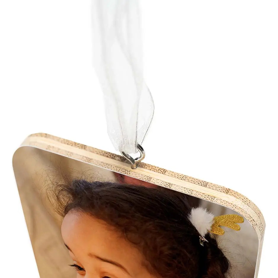 Small child holding a Bamboo Square Ornament photo locket wood hanging from back