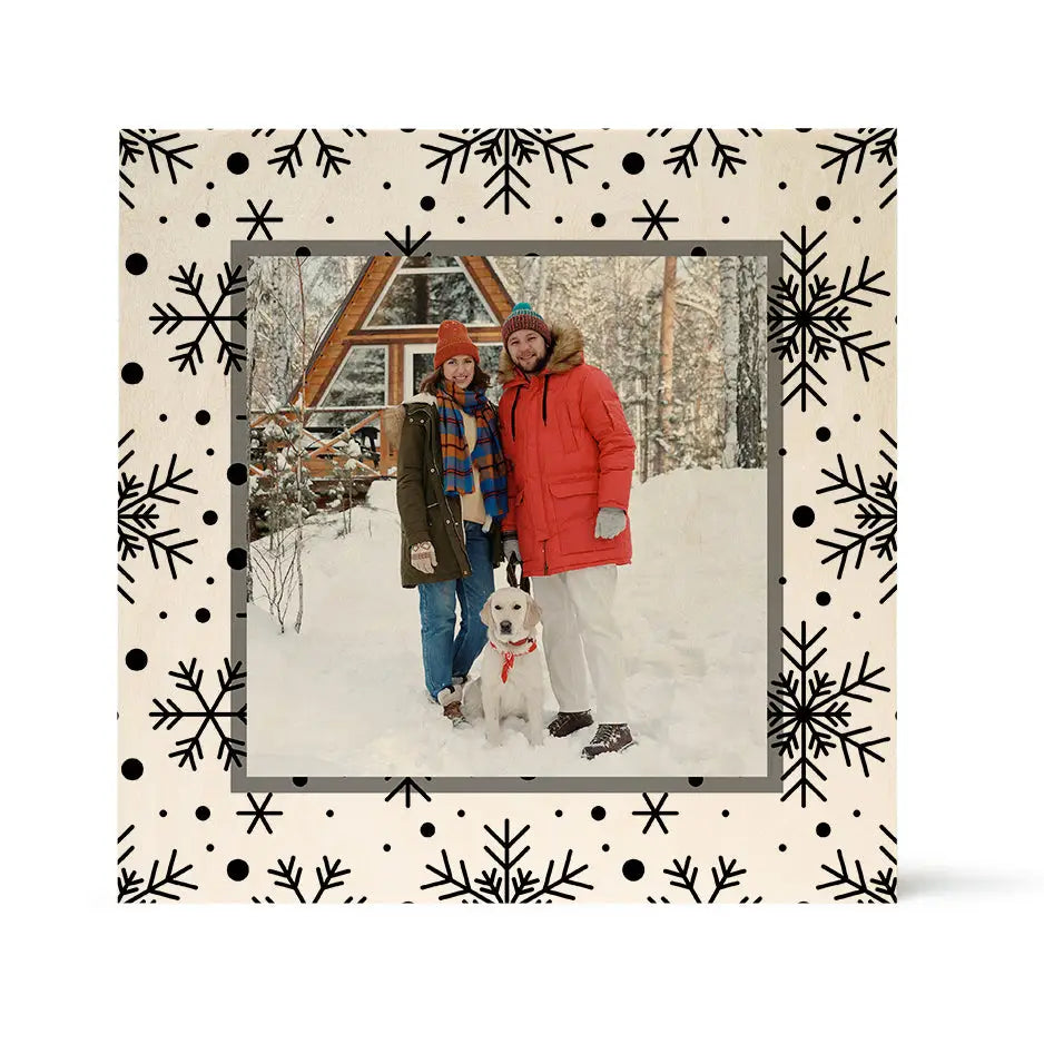 Framed winter photo of two people and a dog at a snowy cabin with birch pattern wood print