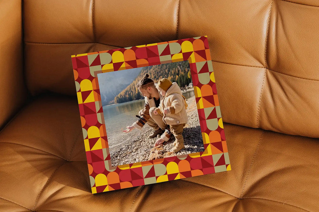 Framed photograph on a beach displayed in a colorful geometric patterned frame.