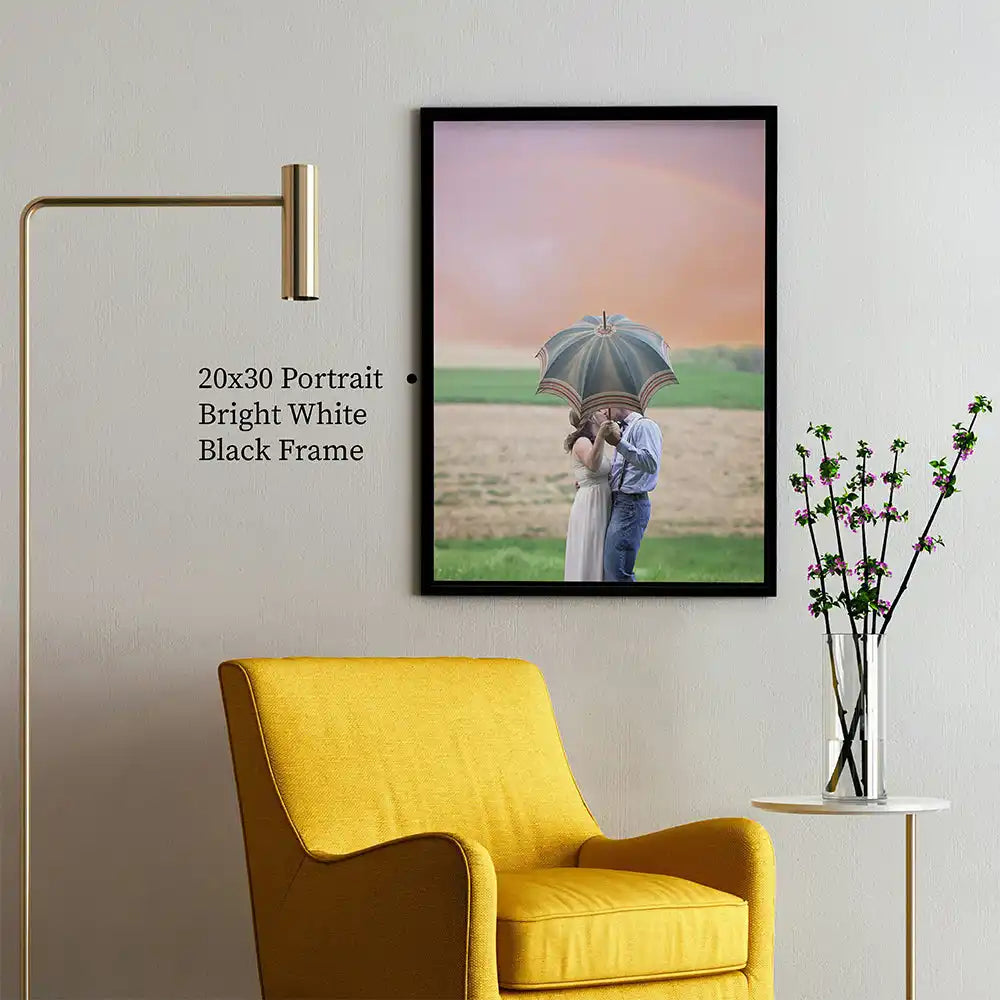 Framed photograph of a couple holding an umbrella in a field at sunset.