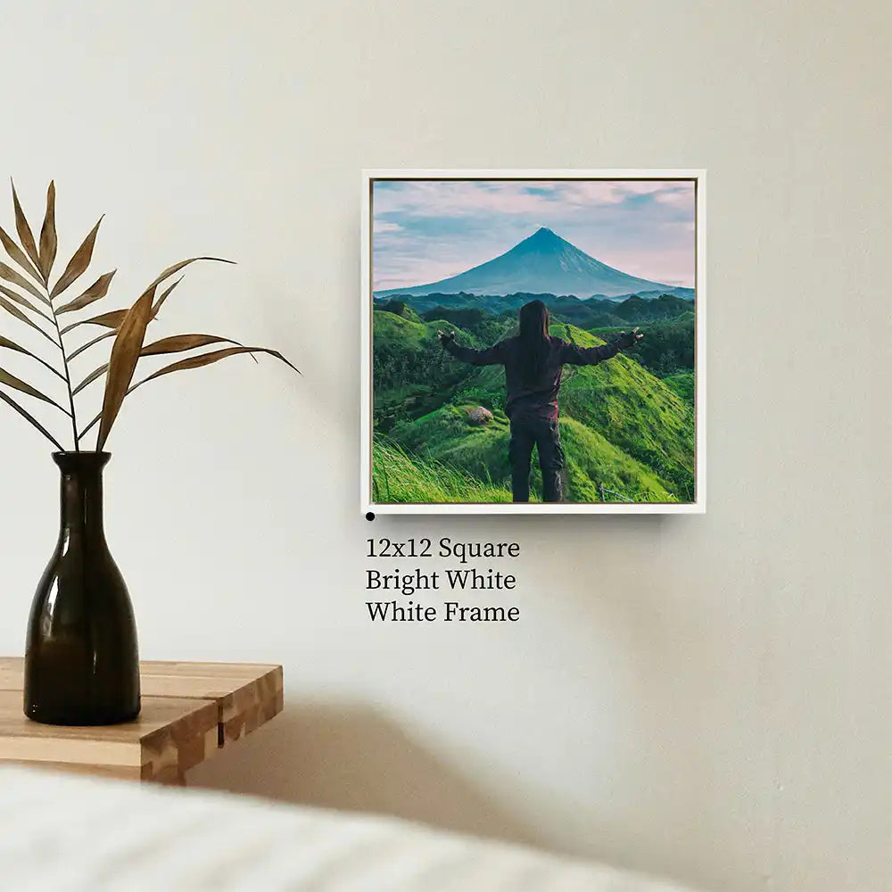 Framed photograph of a silhouetted figure standing on green hills with a mountain peak in the distance.