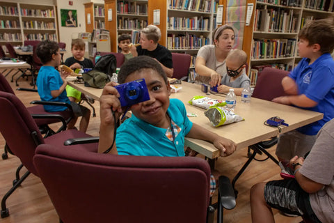 Group of children and adults engaging in kindness activities at a library for Pablove Foundation.