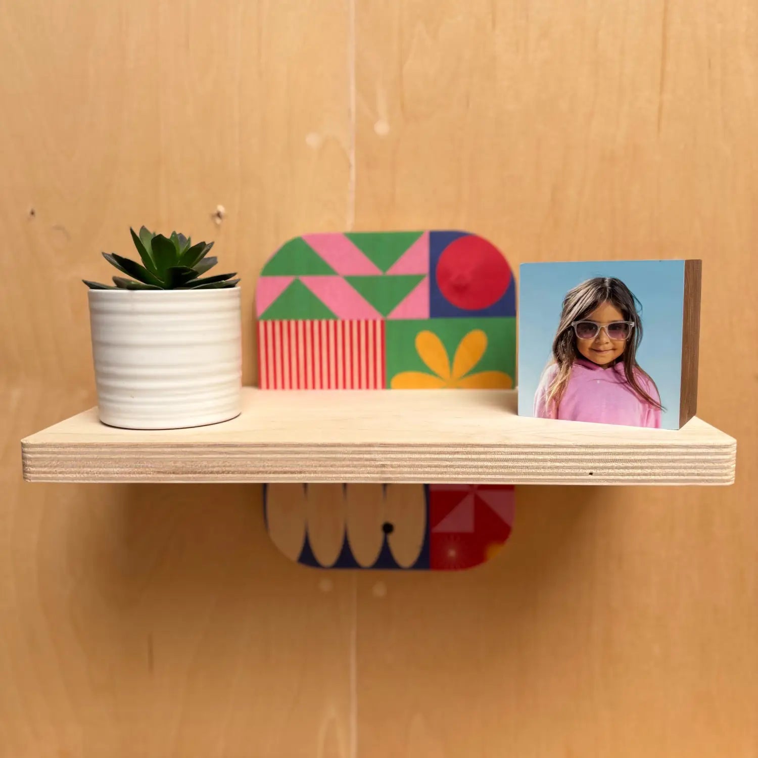 Light-colored wooden floating shelf with colorful decor on Sturdy Wall Shelf Woodsnap’s Simple bracket designs
