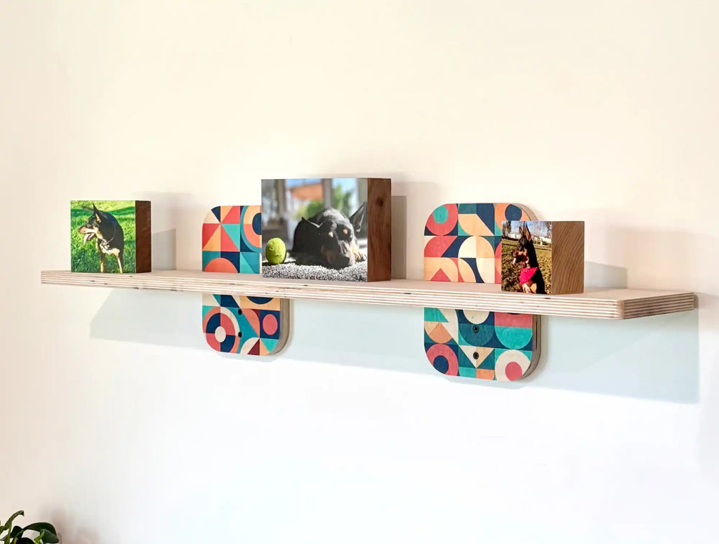A light-colored wooden shelf adorned with several photo blocks and decorative supports, featuring vibrant geometric patterns.