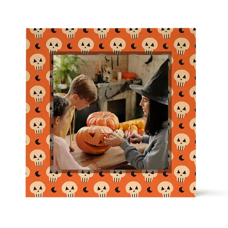 Framed children carving a Halloween pumpkin on a Pattern Wood Print with skulls border