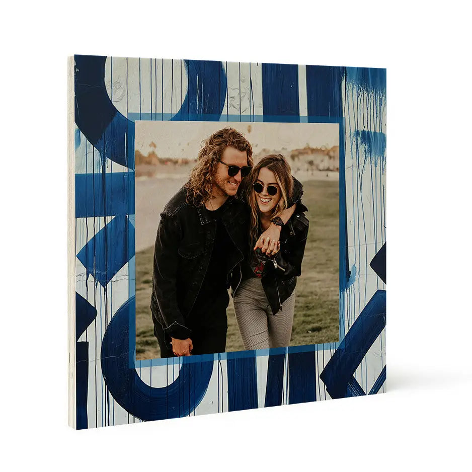 Couple in sunglasses outdoors with wood print frame showcasing stylish blue graffiti