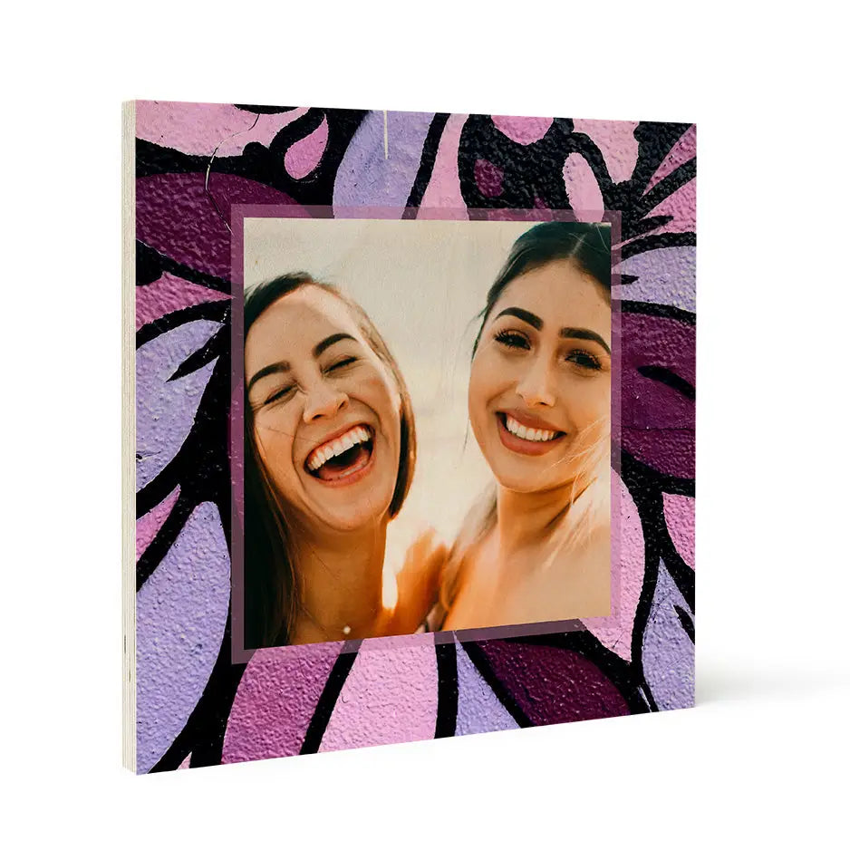 Framed photograph of two smiling women with vibrant purple flower pattern wood print