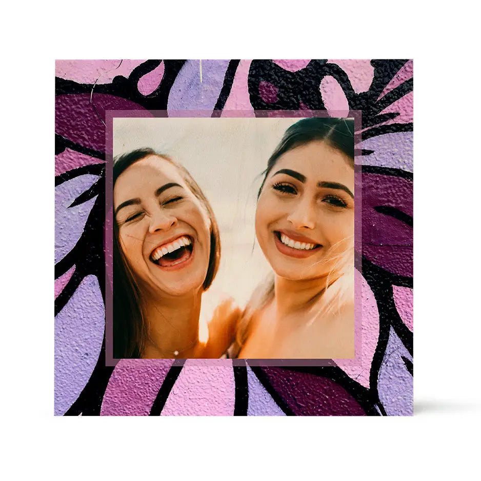 Framed photograph of two smiling women with vibrant purple flower pattern wood print