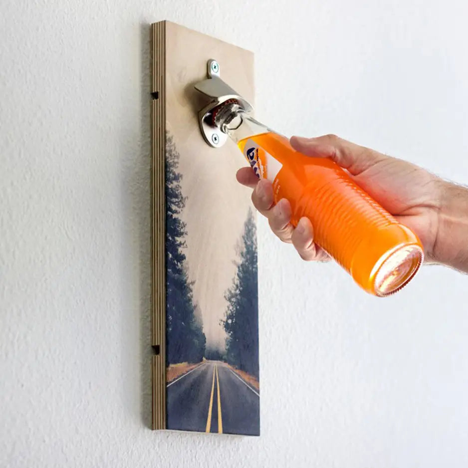 Hand holding a bottle of orange liquid with a Personalized Wood Bottle Opener