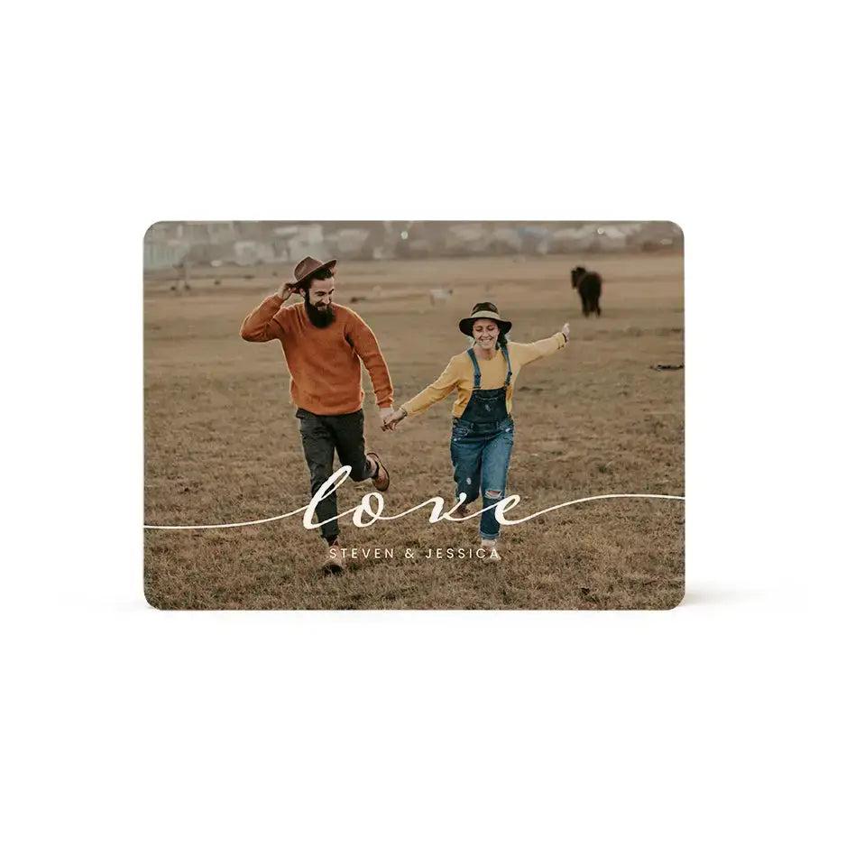 Couple holding hands in a field on a card with Love text above a family wood plaque.