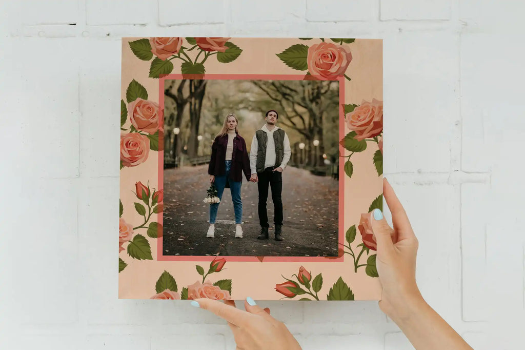 A photograph in a decorative frame with pink roses and green leaves around the border.