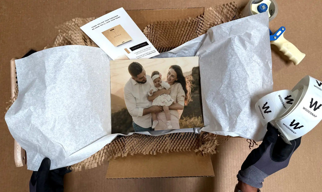 A photograph being unwrapped from white tissue paper on a burlap surface.