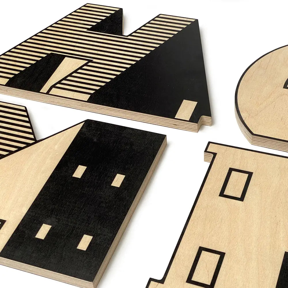 Wooden architectural model pieces with geometric patterns and cutouts in black and natural wood tones.