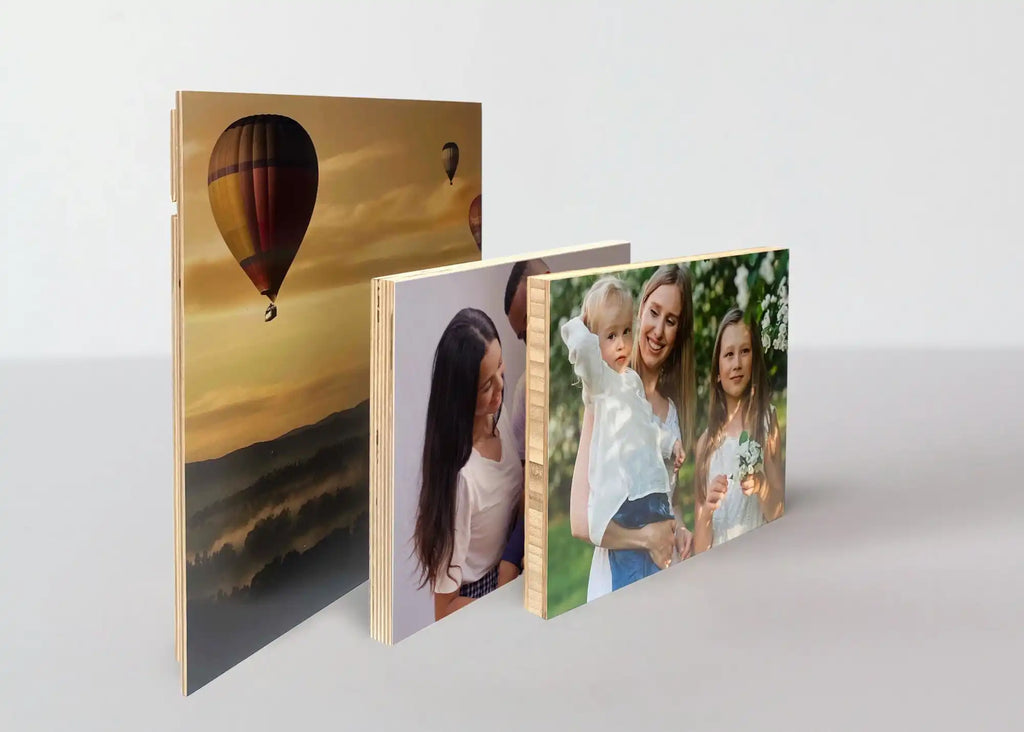 Three photo prints standing upright in a row, displaying a hot air balloon scene and personal photographs.