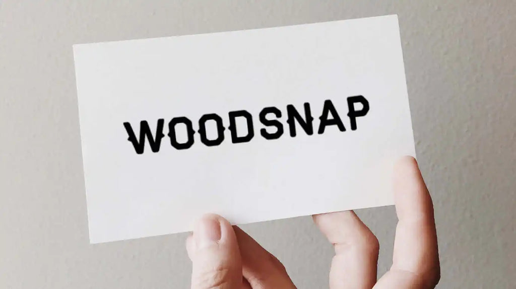 White card or paper displaying the text ’WOODSNAP’ in black letters.